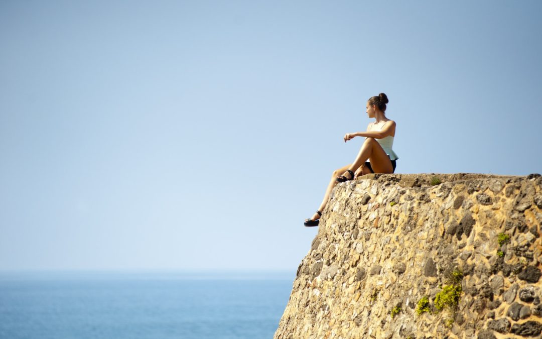 A woman maintaining a healthy gut microbiome while sitting on the edge of a stone wall.