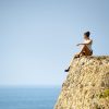 A woman maintaining a healthy gut microbiome while sitting on the edge of a stone wall.